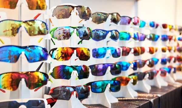 Étalage de lunettes de soleil colorées disposées sur présentoirs blancs dans un magasin d'optique