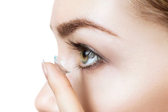 Jeune femme appliquant une lentille de contact transparente sur son œil avec son index